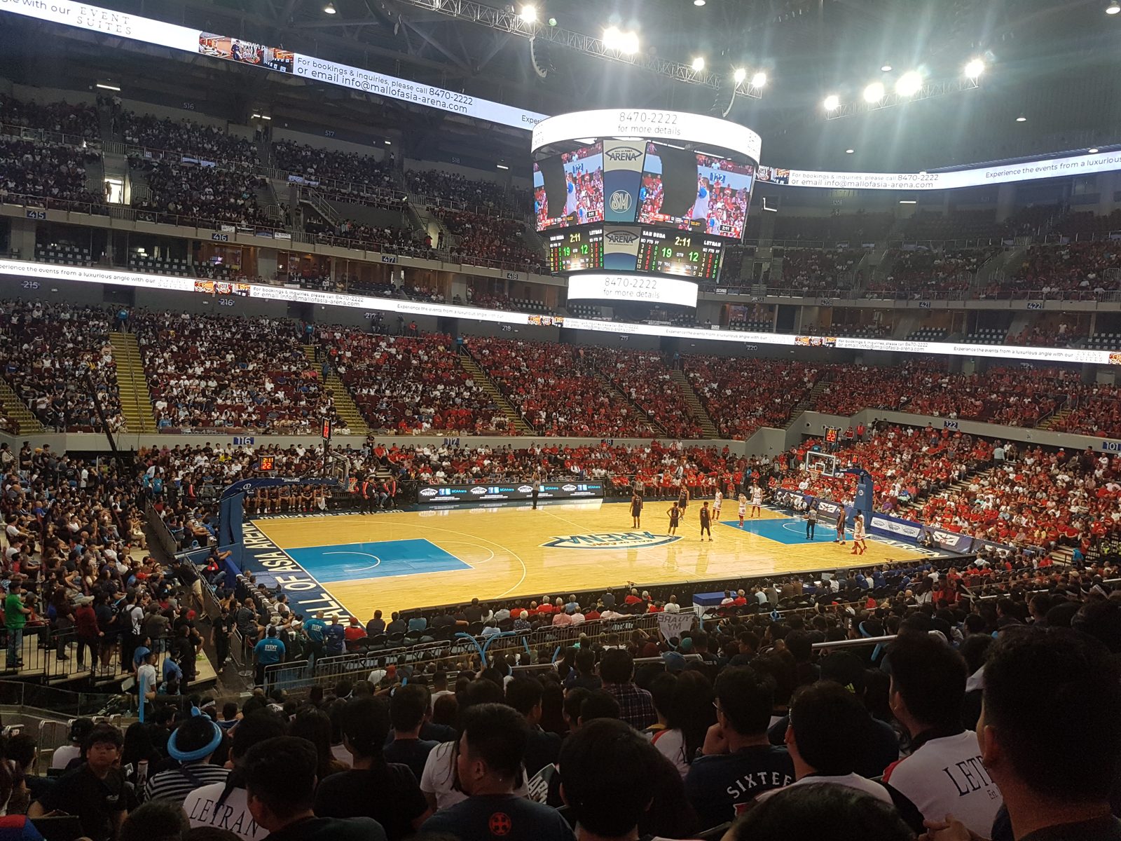 A packed basketball arena crowd watches a game from the stands