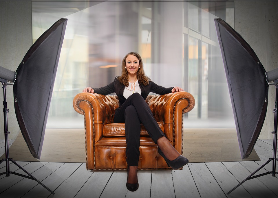 A woman in a black blazer and trousers posing in a studio setting