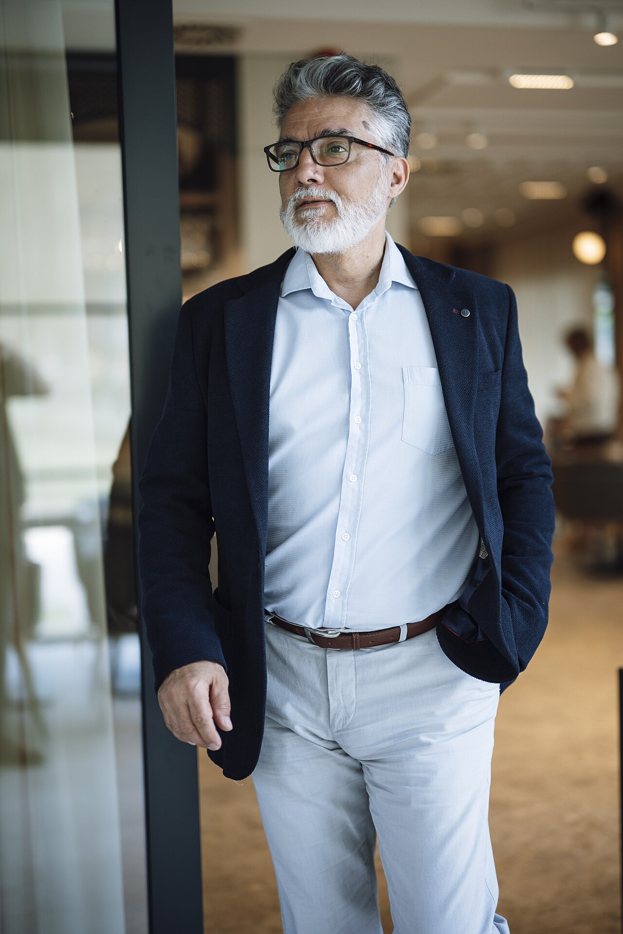 A business professional in a blazer and light trousers standing in a modern office