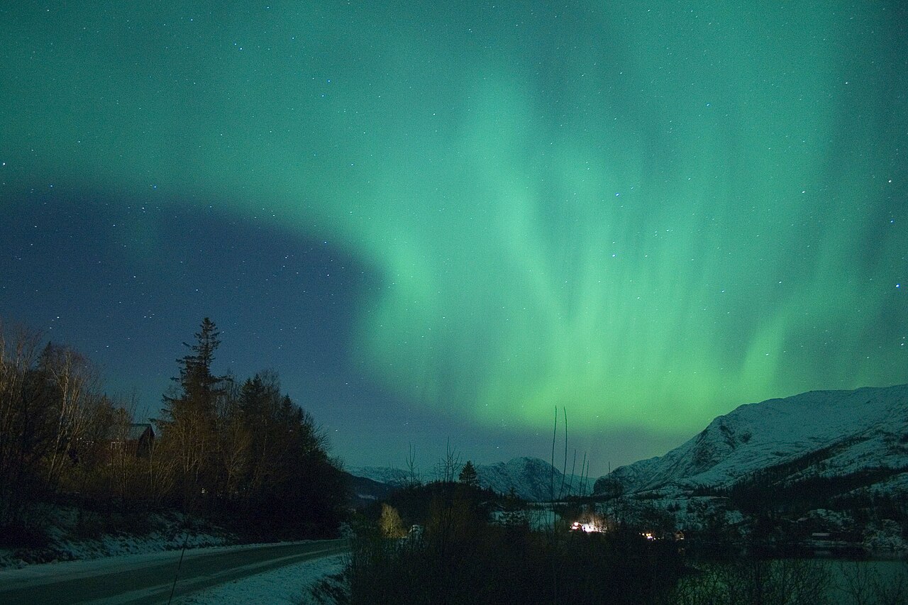 Green aurora borealis glowing over a dark horizon