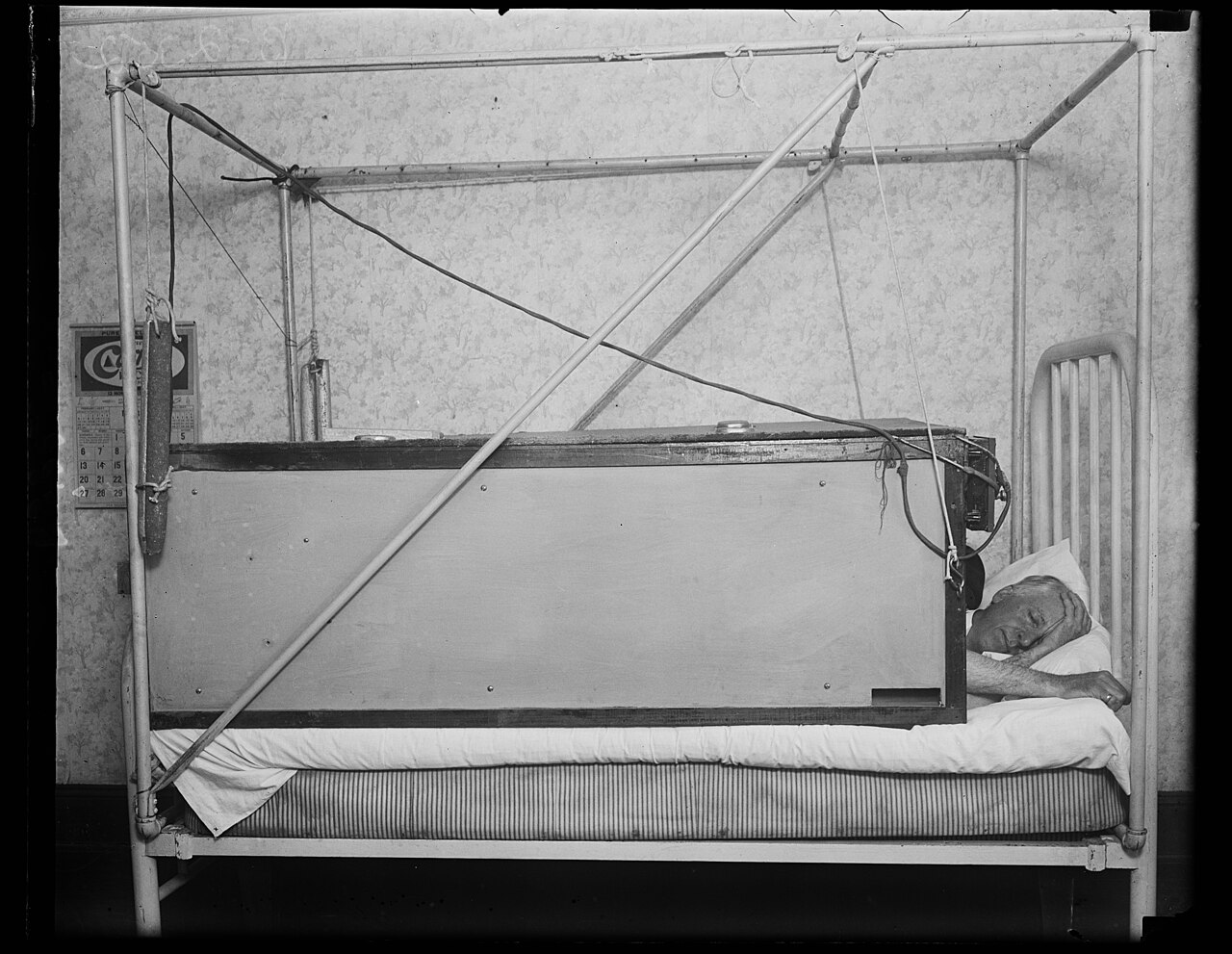 A man sleeps in bed in a historical photograph