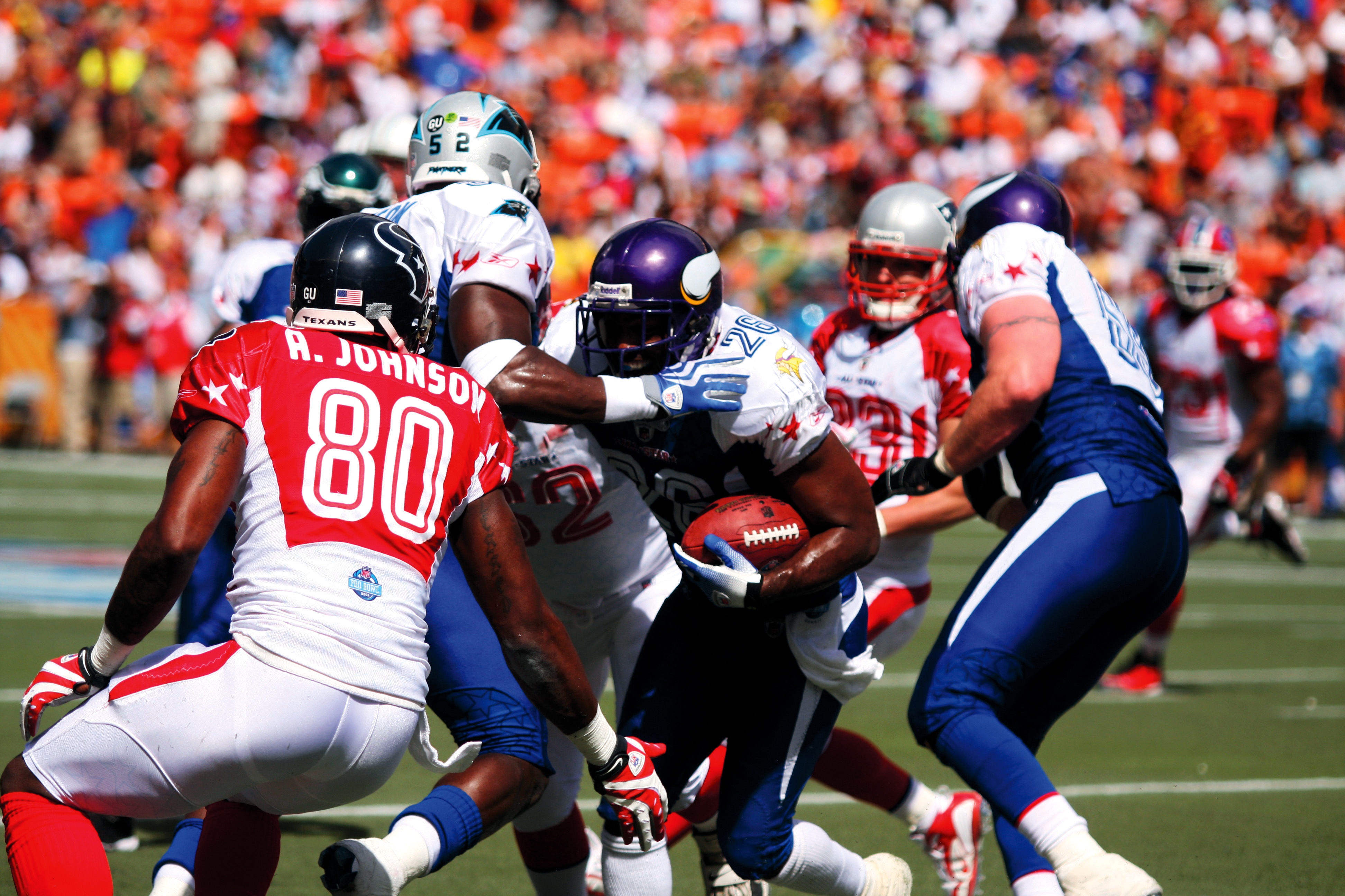 A running back pushes through defenders in a pro football game