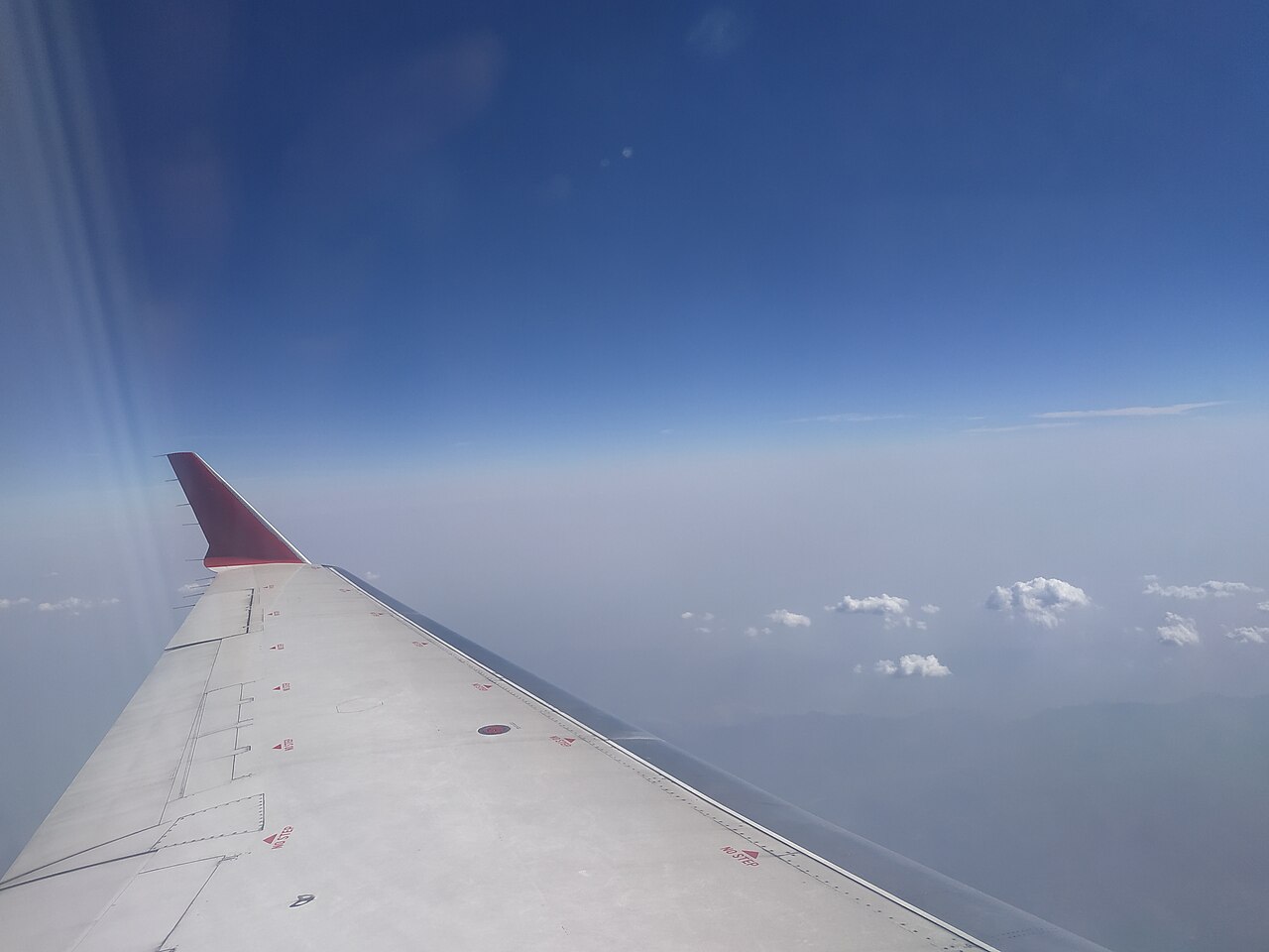 An airplane wing over clouds seen from a window seat