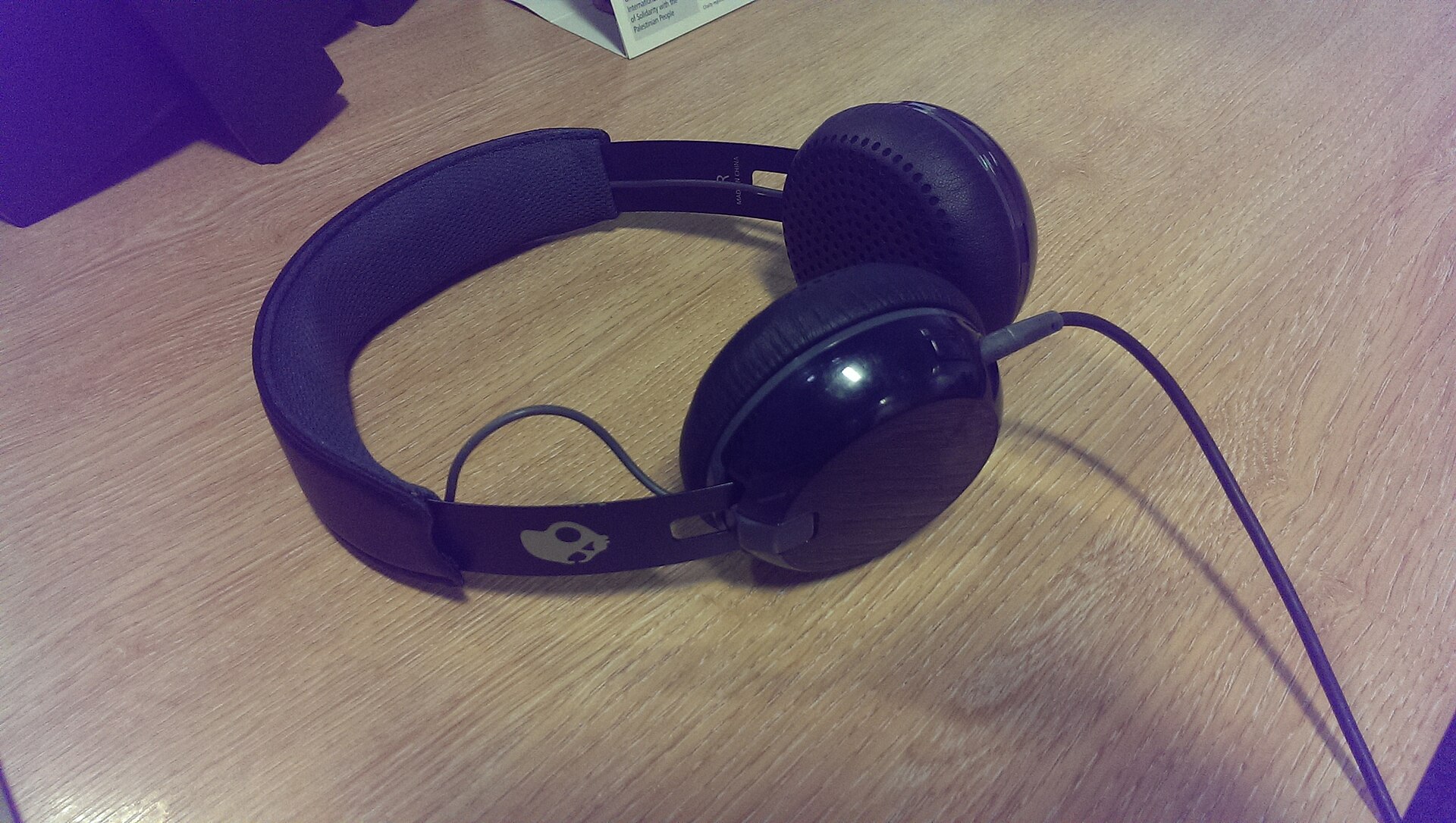 A pair of headphones rests on a desk next to a laptop