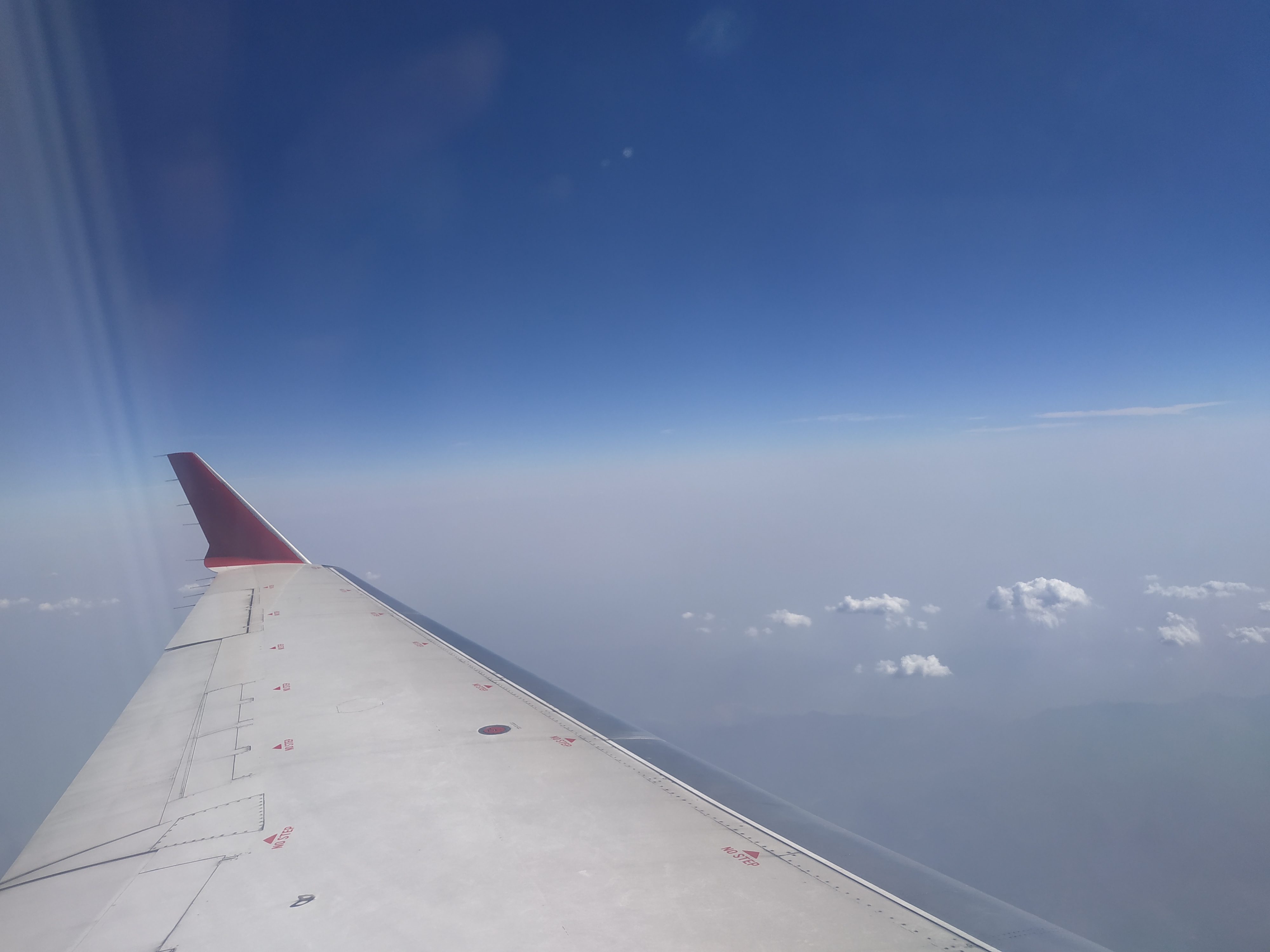 An airplane wing seen from a passenger window above the clouds