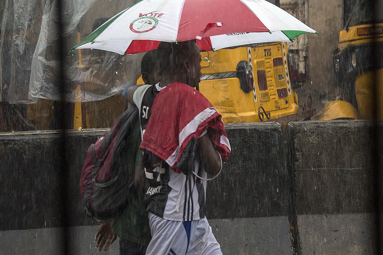 Two children sharing an umbrella in heavy rain