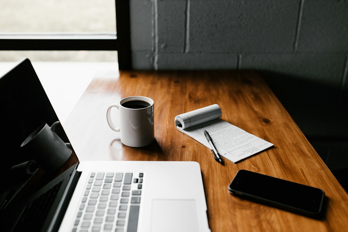 Professional working at a laptop with coffee, continuing the job search