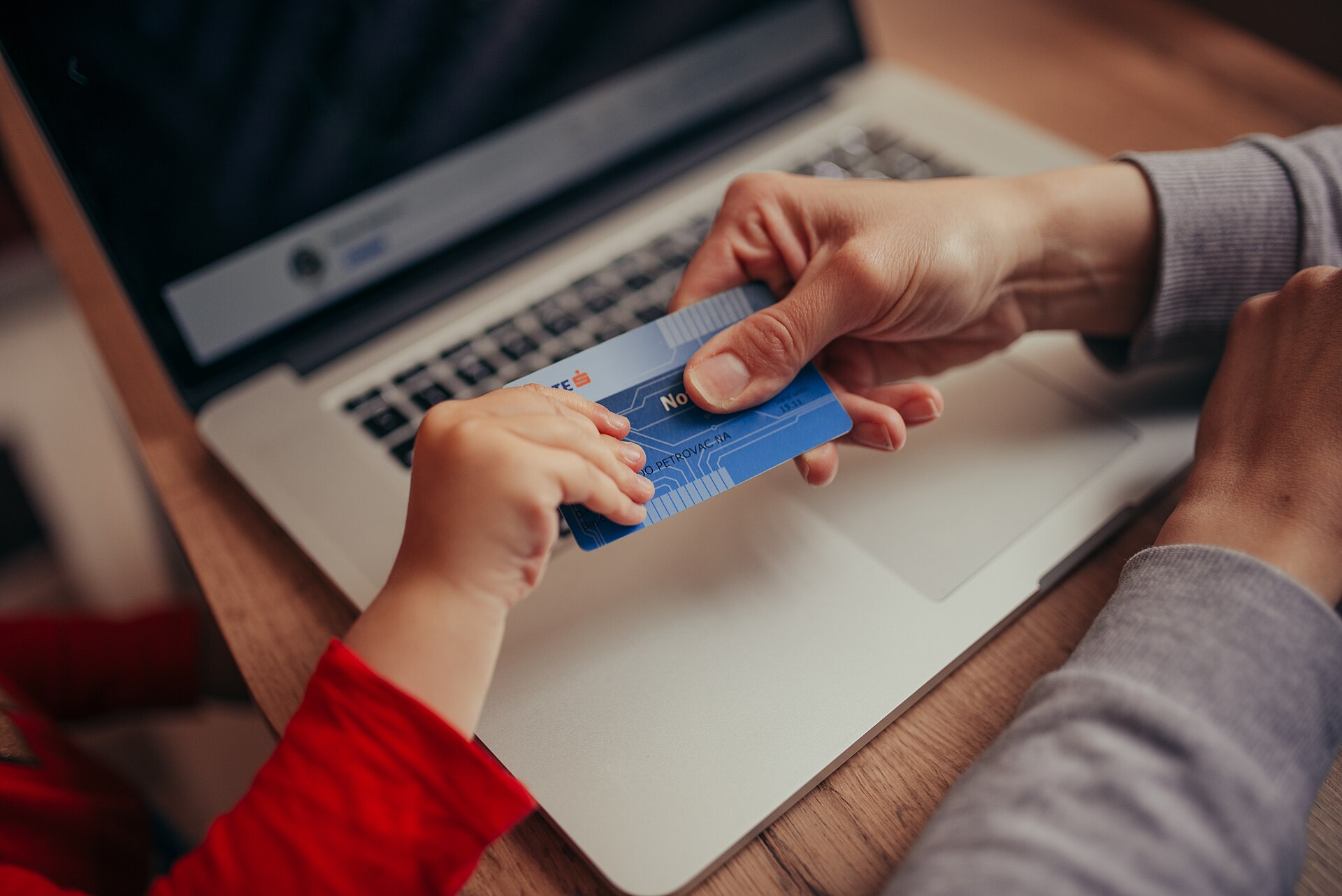 A person holds a credit card in front of an open laptop