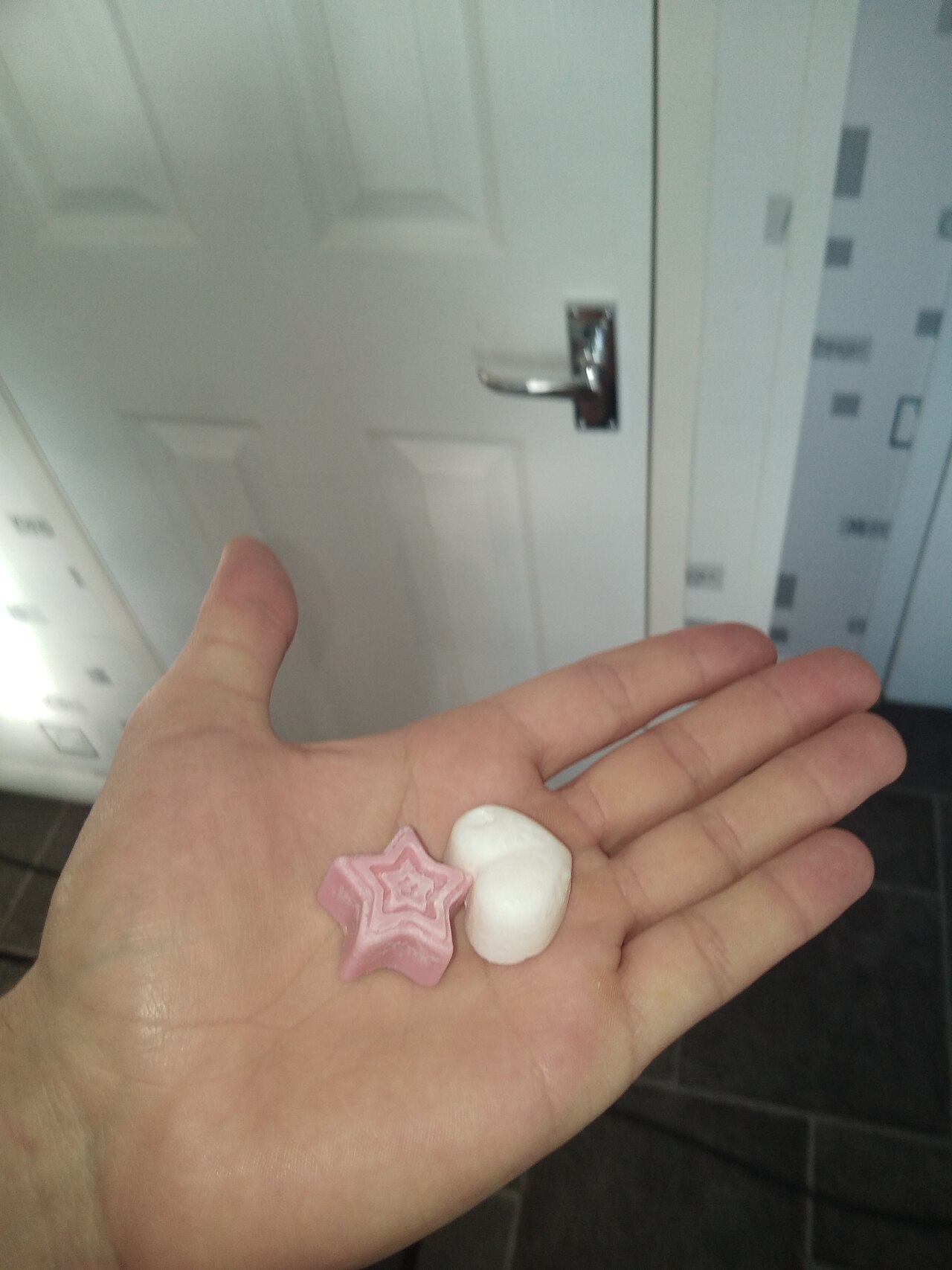 Two small wax melts held in a hand, made of the same paraffin that bonds to carpet