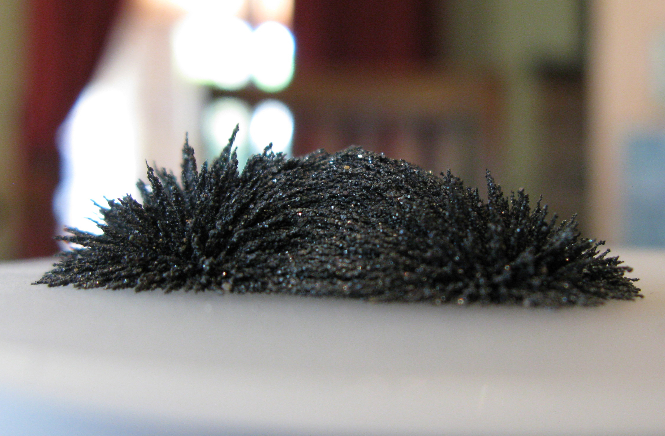 Iron sand clinging to a magnet in spiky patterns