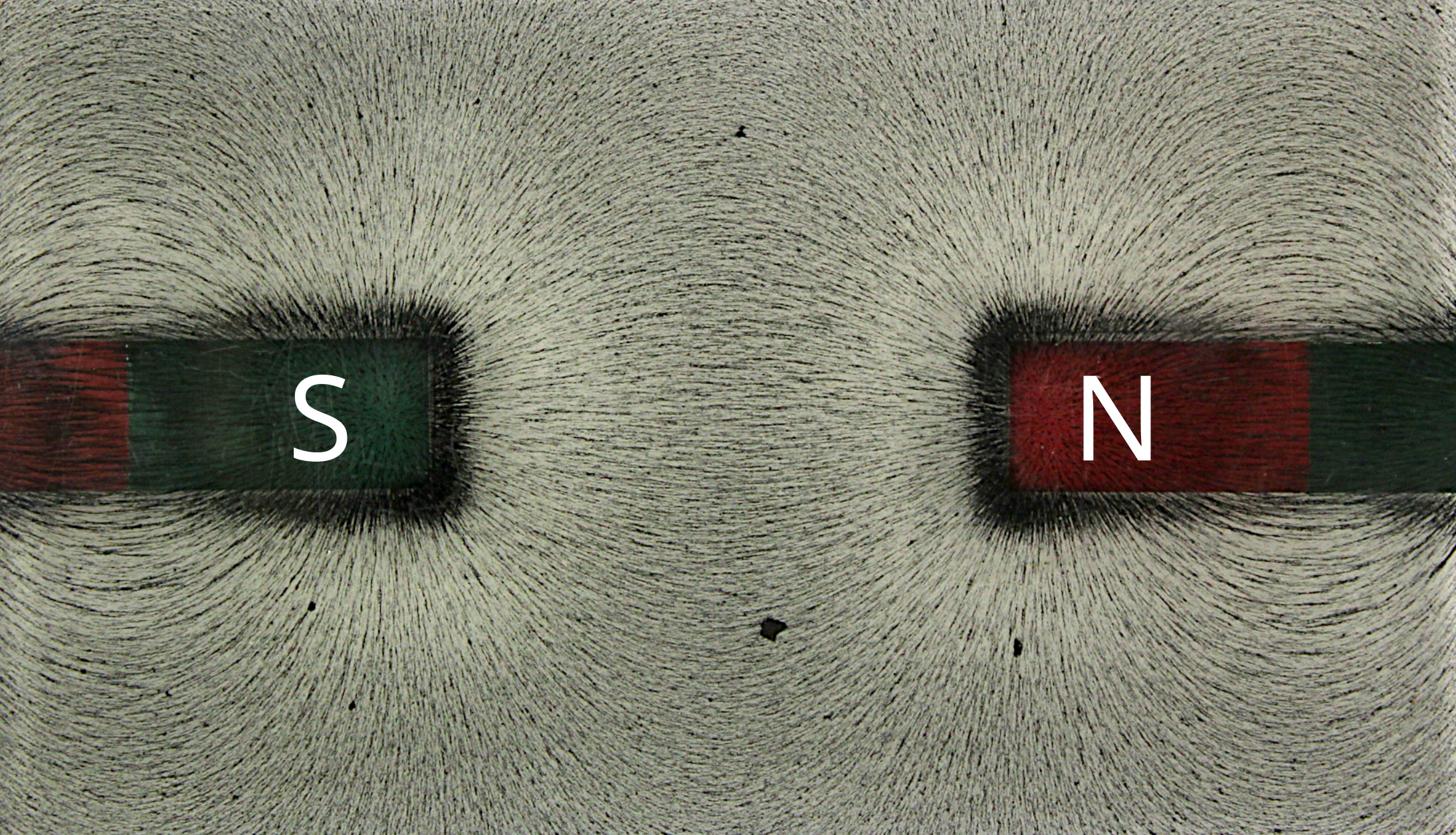 Bar magnets attracting iron filings into curved field patterns