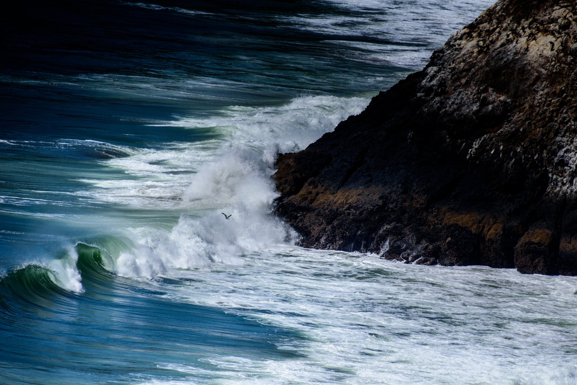 Waves crashing against a rocky coastline with spray flying