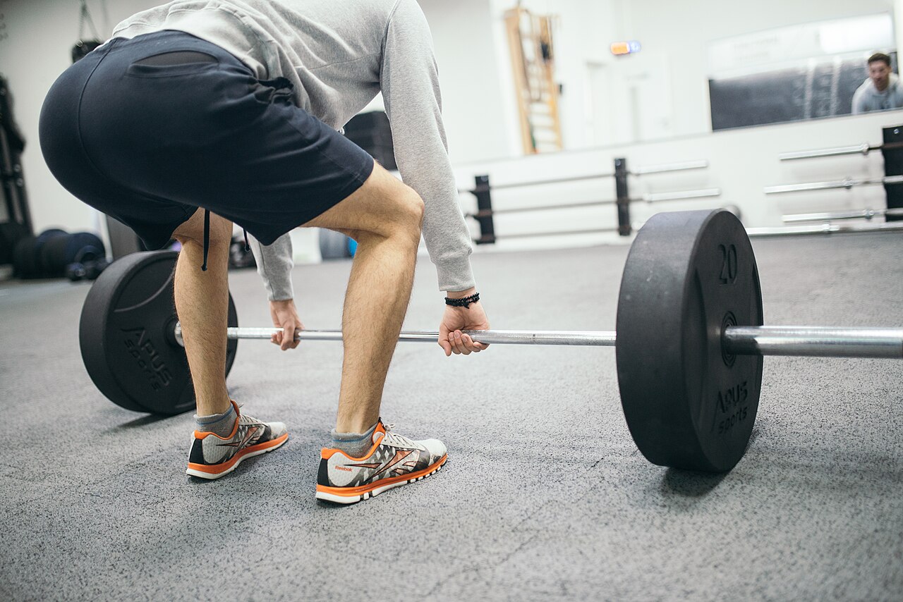 A young man performing a deadlift exercise in a gym