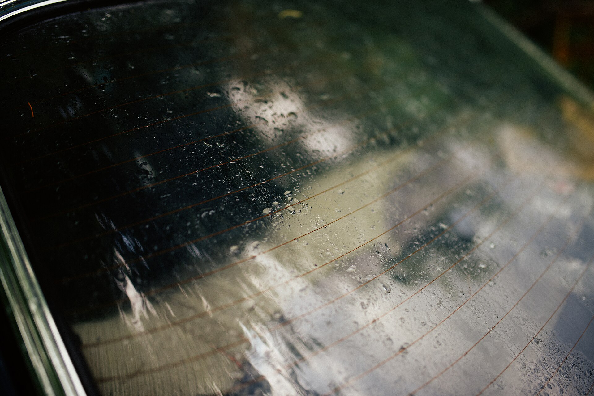 Rain droplets on a car rear window with defroster lines