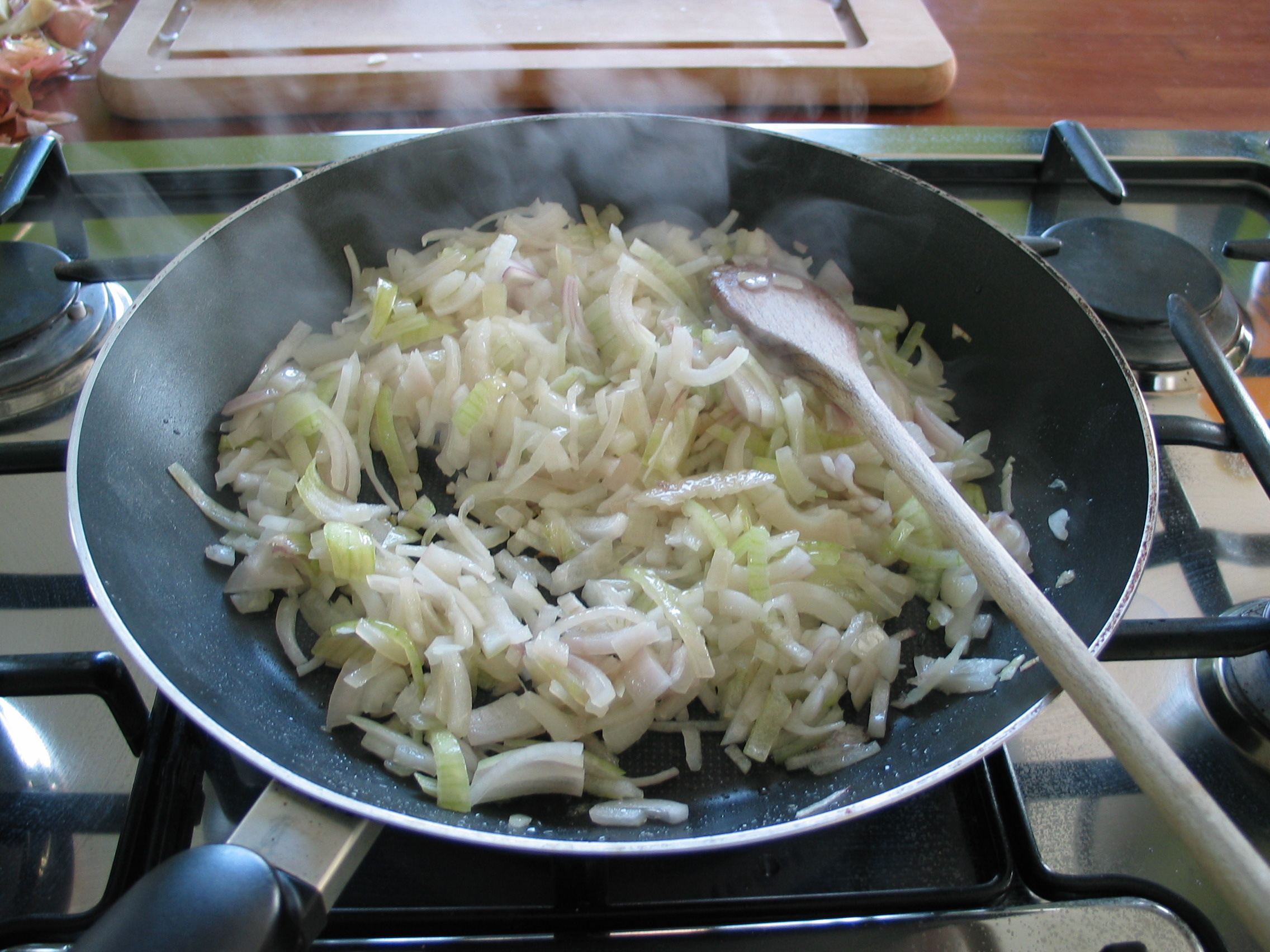 Sliced onions cooking in a frying pan on the stovetop