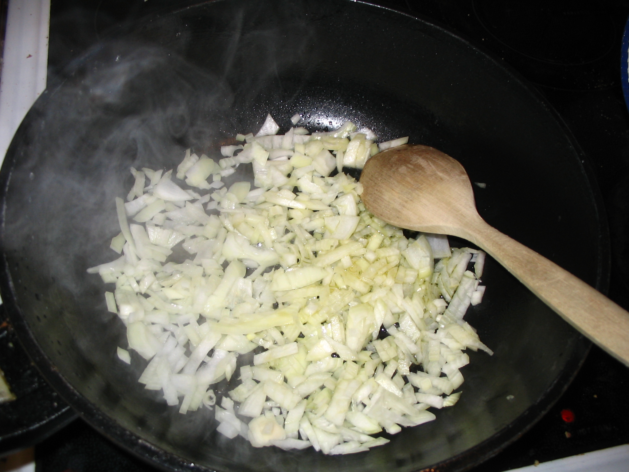Onions frying in a pan with oil, starting to turn golden at the edges