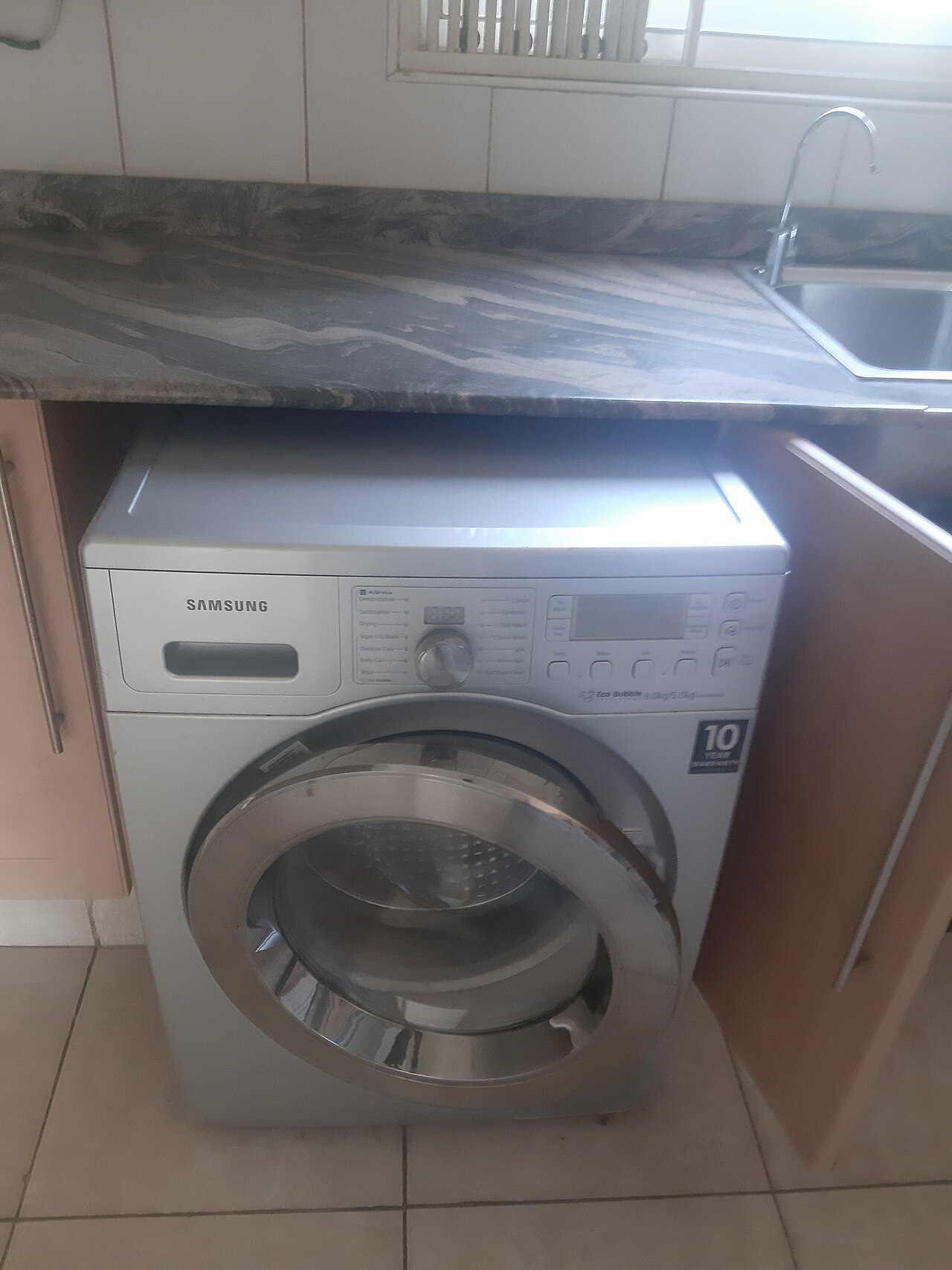 A front-load washing machine with its round door in a home laundry area