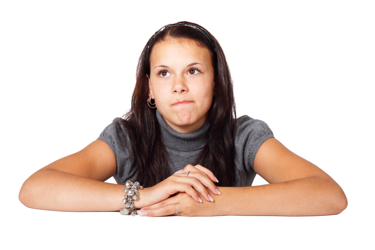 A pensive teenage girl resting her chin on her hands
