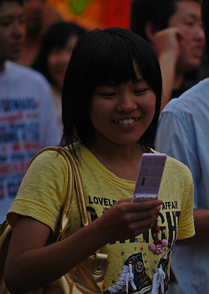 A teenager smiling while looking at her mobile phone