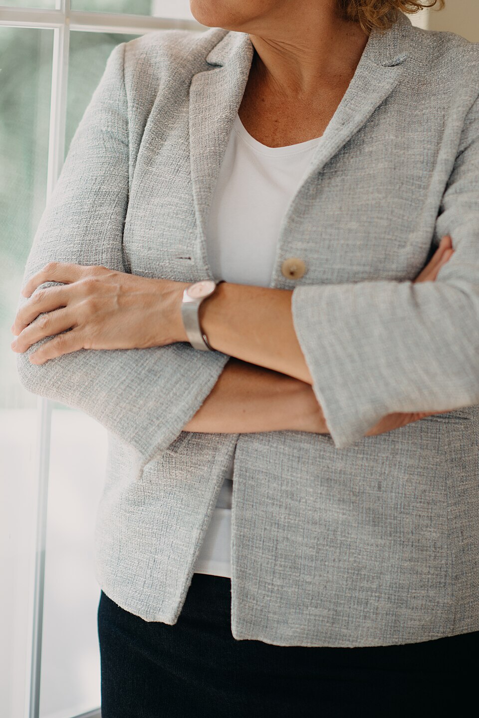 A woman in a gray blazer, the kind of polished top half that reads well on a video interview camera