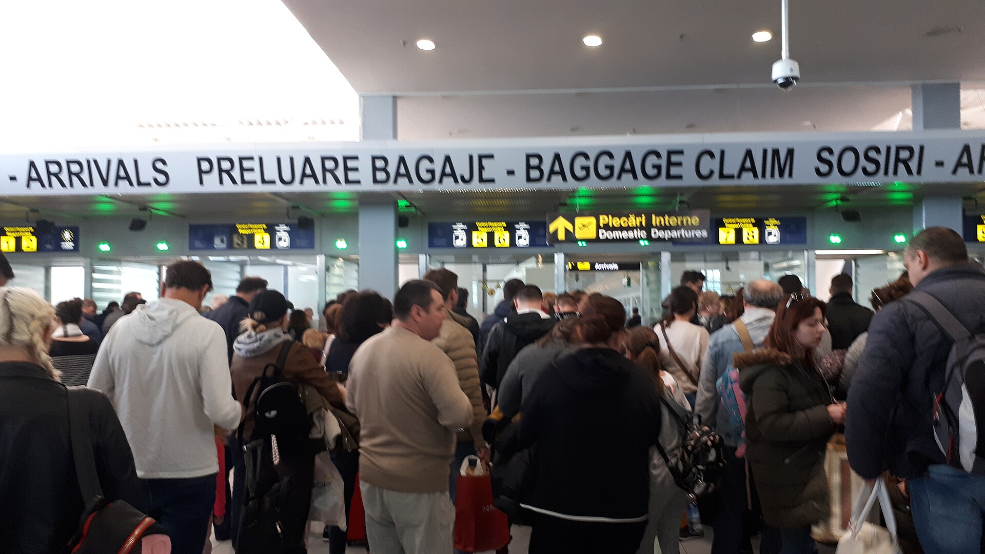 Travellers crowding an airport arrivals hall